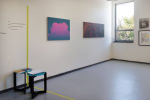 Image: An installation view of Preface.../yet Flavourful. A wide green and yellow tape extends from the floor to the wall on the left side. On the right side of the divided space is Braden Bandel, Pink Cloud, 2023, Oil on canvas, 26 1/2 x 34 1/2 inches. Next to it hangs Braden Bandel, Cloud Diptych, 2019, Oil on canvas, in two parts, 24 x 30 inches each. Further to the right is a window, followed by the central wall. On this wall hangs Braden Bandel, Story Mode III, 2021, Ink on paper, with Dasha Shishkin, onions, 2021, Watercolor monotype, Image size 16 3/4 x 13 inches, paper size 22 x 15 inches, closely positioned below it. Photo by Tianjiao Wang.