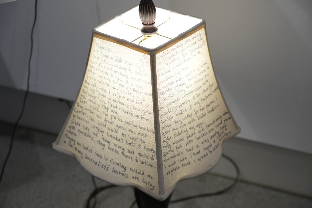 Image: Detail view of Dreaming in Letters, 2024. A beige lampshade is covered with the text of a letter. Photograph by Curators Under Censorship.