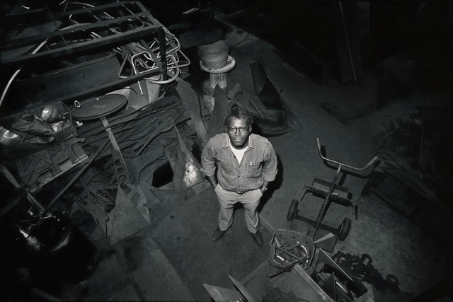 Image: Richard Hunt in Lill Ave Studio. A photo from above shows the artist by a work table and surrounded by sculptures in progress. © 2024 The Richard Hunt Trust / Artists Rights Society (ARS), New York.