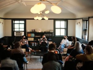 Image: A group of writers and editors sit and listen to a a panel discussion at Sixty's Midwest Arts Writers Convening. The event took place at Haymarket House from April 27-29, 2025. Image made by Seed Lynn (@seedlyn).
