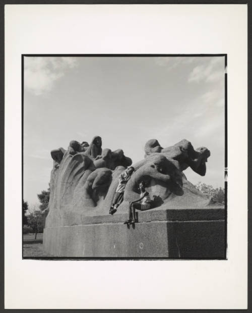 Image: A black and white photograph taken in 1994 of two young Black kids on the Fountain of Time in Washington Park. Wearing a short-sleeve shirt and shorts, the young boy balances his stand while resting his head on the monument and looking at the camera. The young girl, seemingly a few years older, also looks at the camera with her left arm extended and hand on her right knee. Photo Credit: James Iska, Courtesy of Chicago Park District Records: Photographs at the Chicago Public Library. Special Collections & Preservation Division, Digital Link.