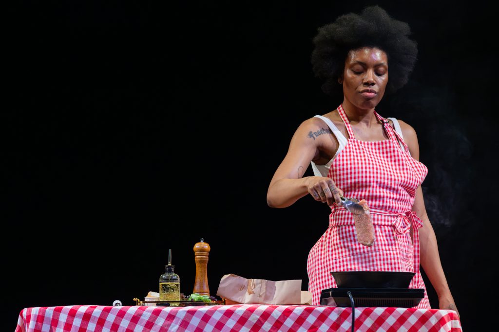 Image: Freeman | Po'Chop weighs meat on a table on the stage. Photo by Natasha Moustache.
