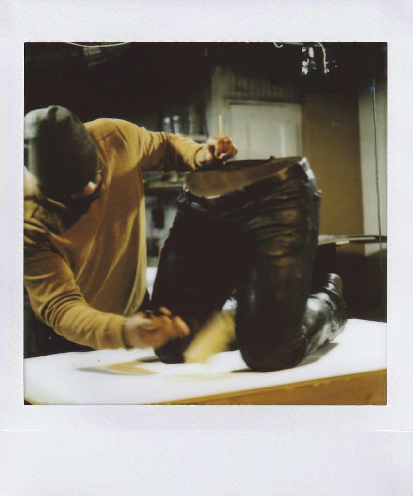 Image: Polaroid of Michael Coppage dusting a bronze sculpture. Photo by Asa Featherstone, IV.