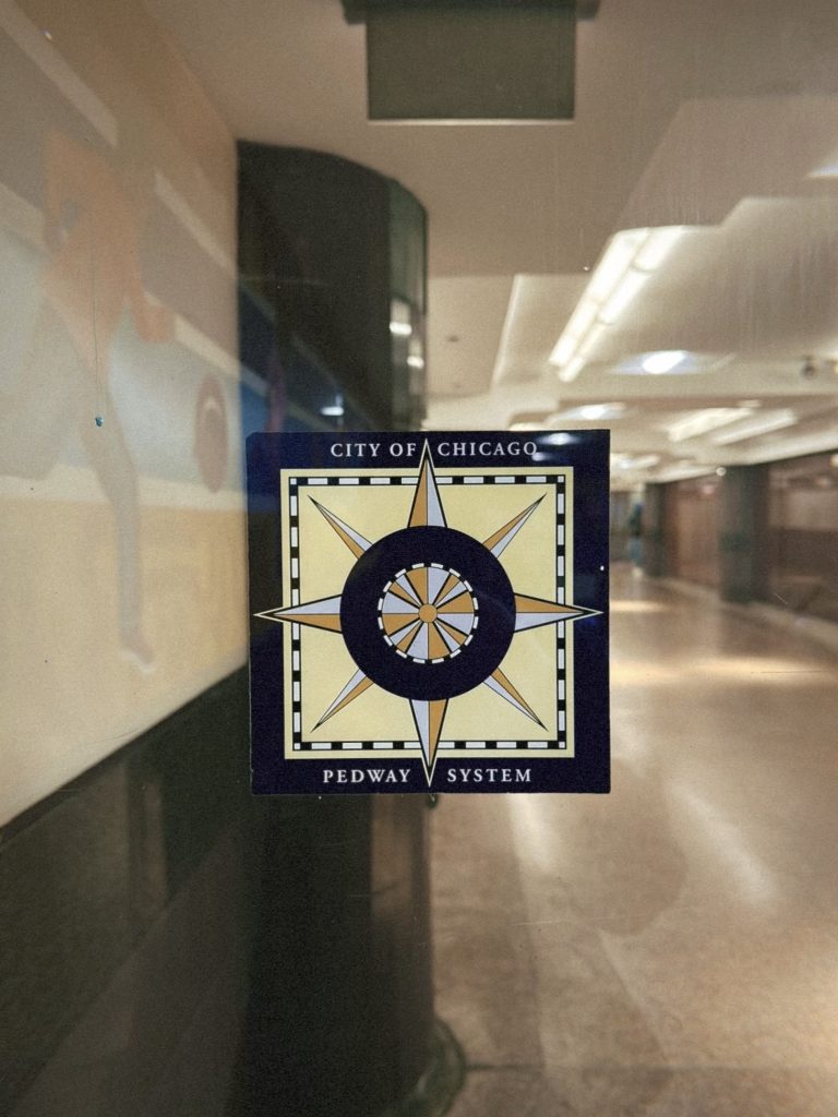 Image: A window view of the Chicago underground pedway system. The pedway's logo is front and center. Image by Livy Snyder.