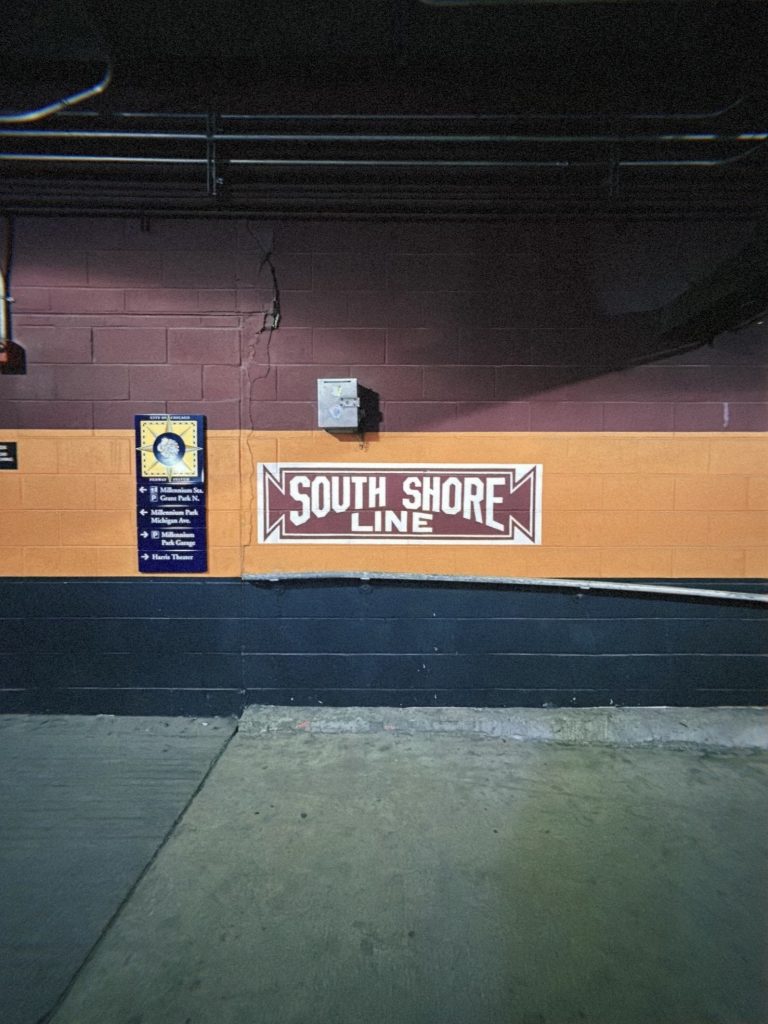 Image: Image of the burgundy and white "South Shore Line" logo shown on the orange wall of the line's pedway. Image by Livy Snyder.