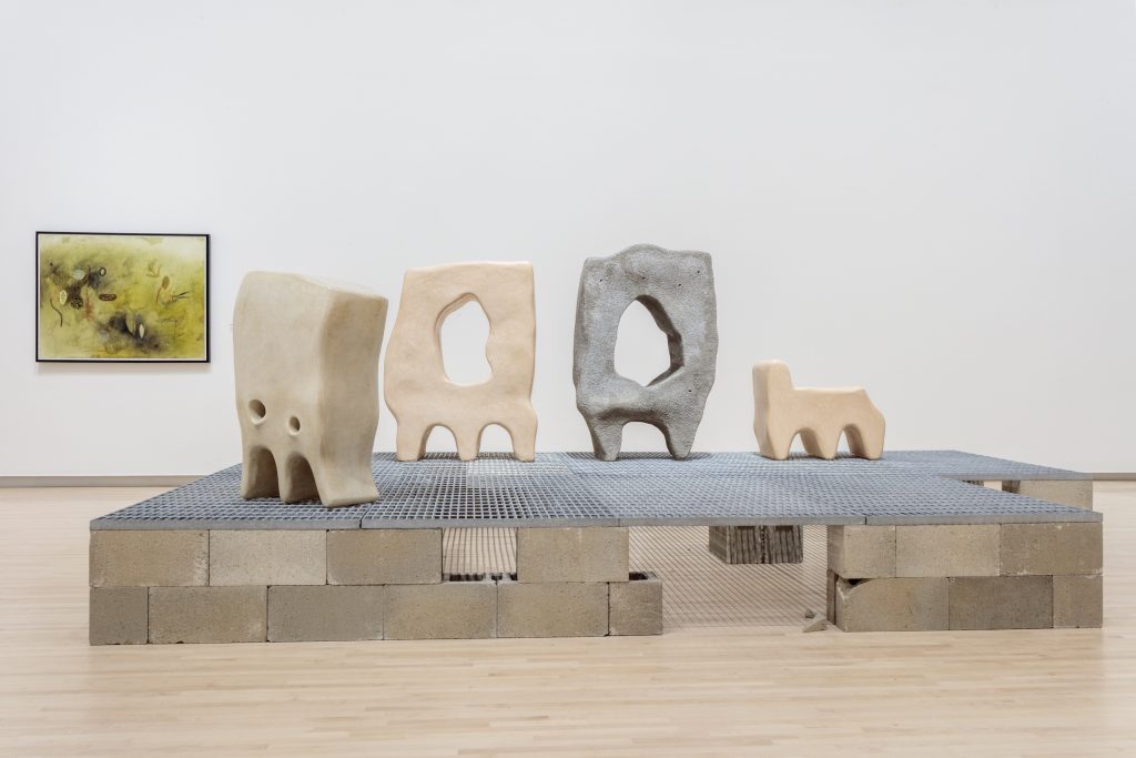 Image: Installation view of Seeds: Containers of a World to Come at the Kemper Art Museum, Washington University in St. Louis (February 21–July 28, 2025). Photo by Joshua White / JWPictures.com. Jumana Manna’s installations Family and Ghost II (Cache Series) can be seen on display. Earth-tone vessels that resemble ancient grain containers known as khabyas sit elevated from the gallery floor on concrete and metal stucture.