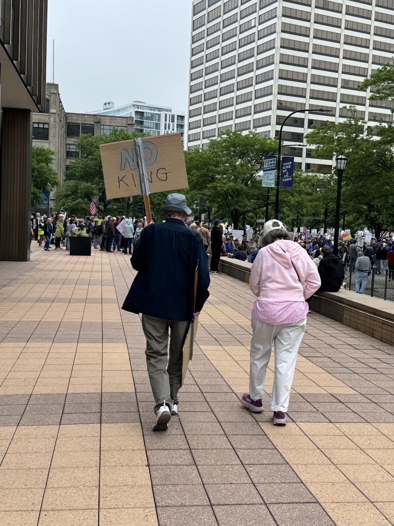Image: Two protestors are joining the crowd with a No King sign. Image courtesy of the author.