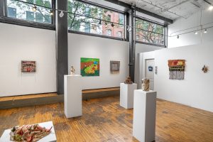Image: Installation View, Eden Through a Glory Hole, 2025, Chicago Art Department. Four pedestals display work with colorful lush scenes on the walls around them. Photo: Mikey Mosher. Courtesy of Tali Halpern.