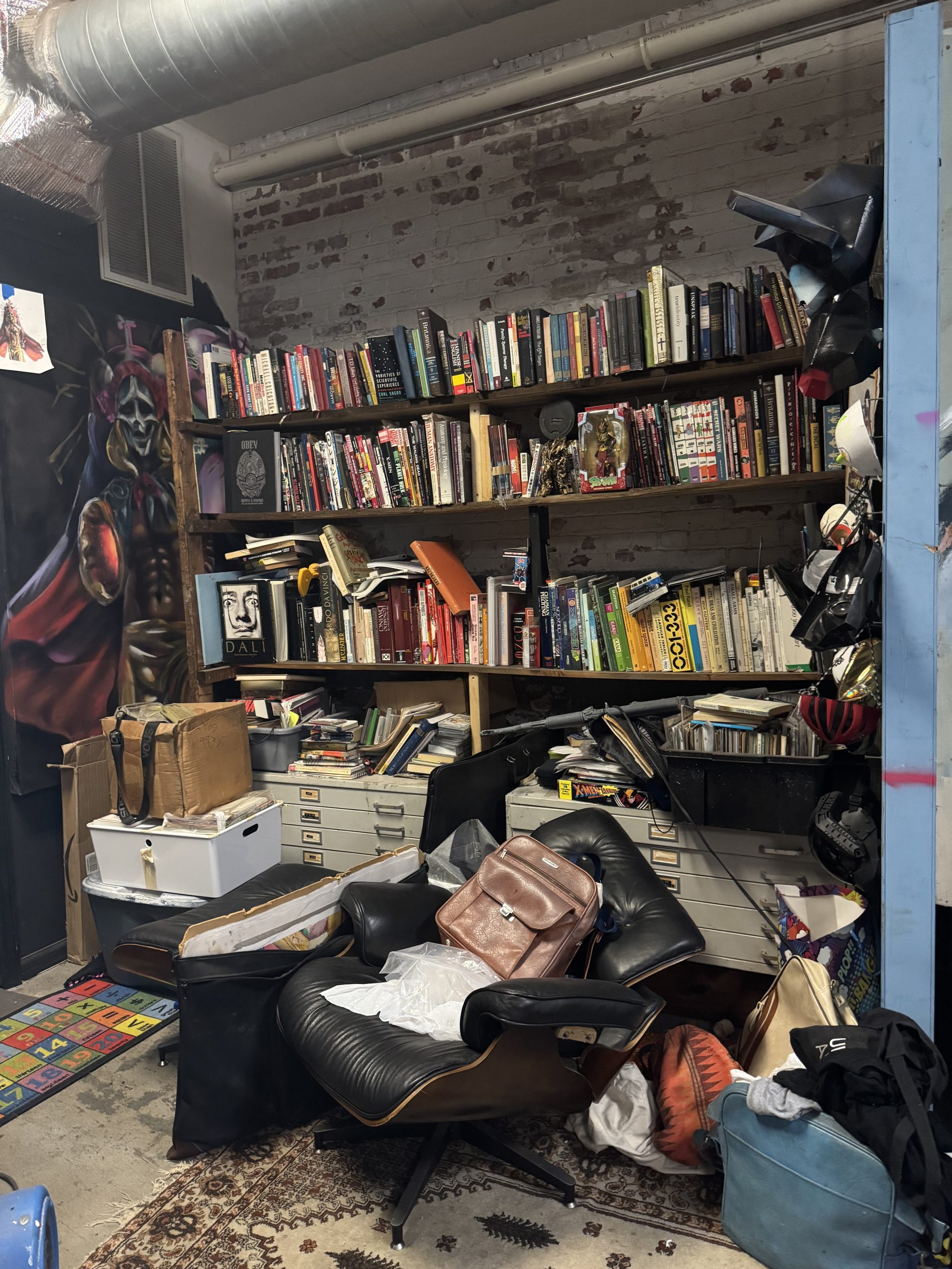 Image: A wall of books among art and various furniture pieces in the BlackBrain Group studio space. Image by Claire Stemen.