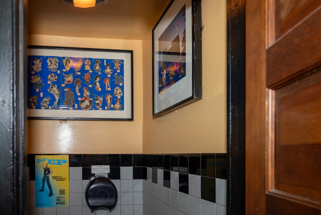 Image: (1-6, above) Fire’s art collection continues to adorn the walls. Various framed art hang on the walls at Big Chicks. Some walls are orange, some green, and some pale yellow. Images by Tonal Simmons.
