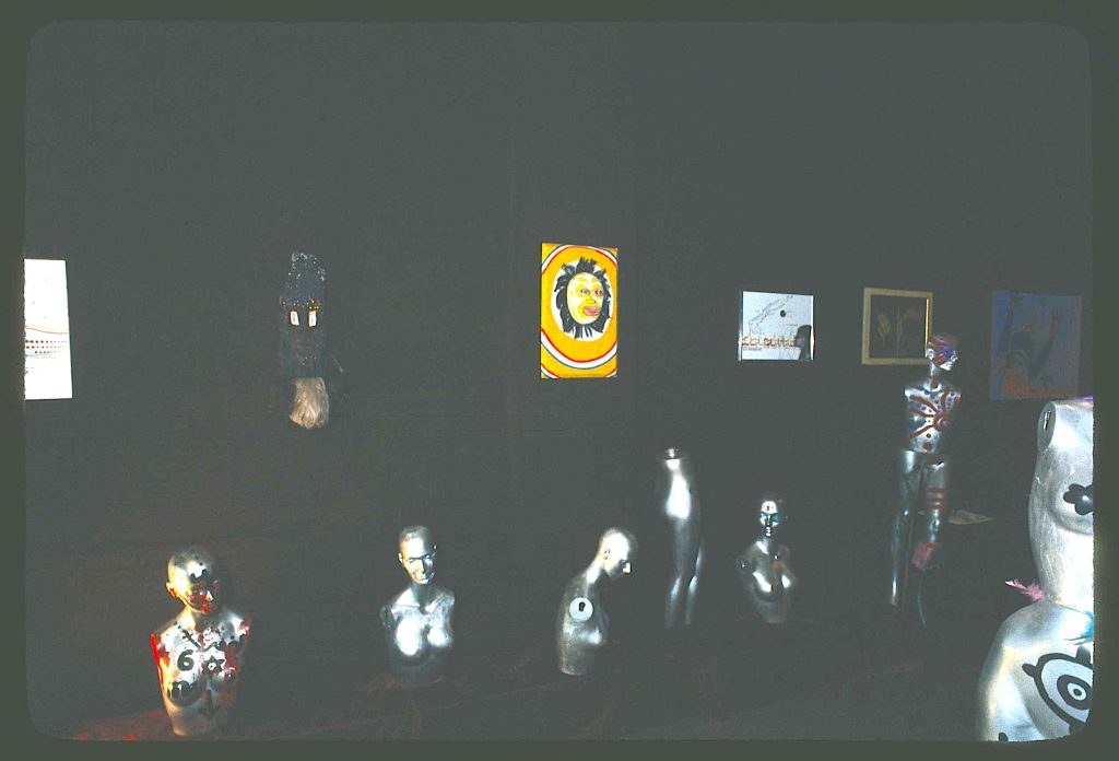 Image: View of Oşun gallery featuring wall hung paintings from various artists and Olu's hand painted mannequins spread throughout the gallery. Image courtesy of the Library of Congress. Image by Jonas Dovydenas for the Library of Congress' Chicago Ethnic Arts Project. Note: The photographer forgot to use flash for his images inside of the studio. This image has been brightened in post by the author to better view the artwork in the gallery.