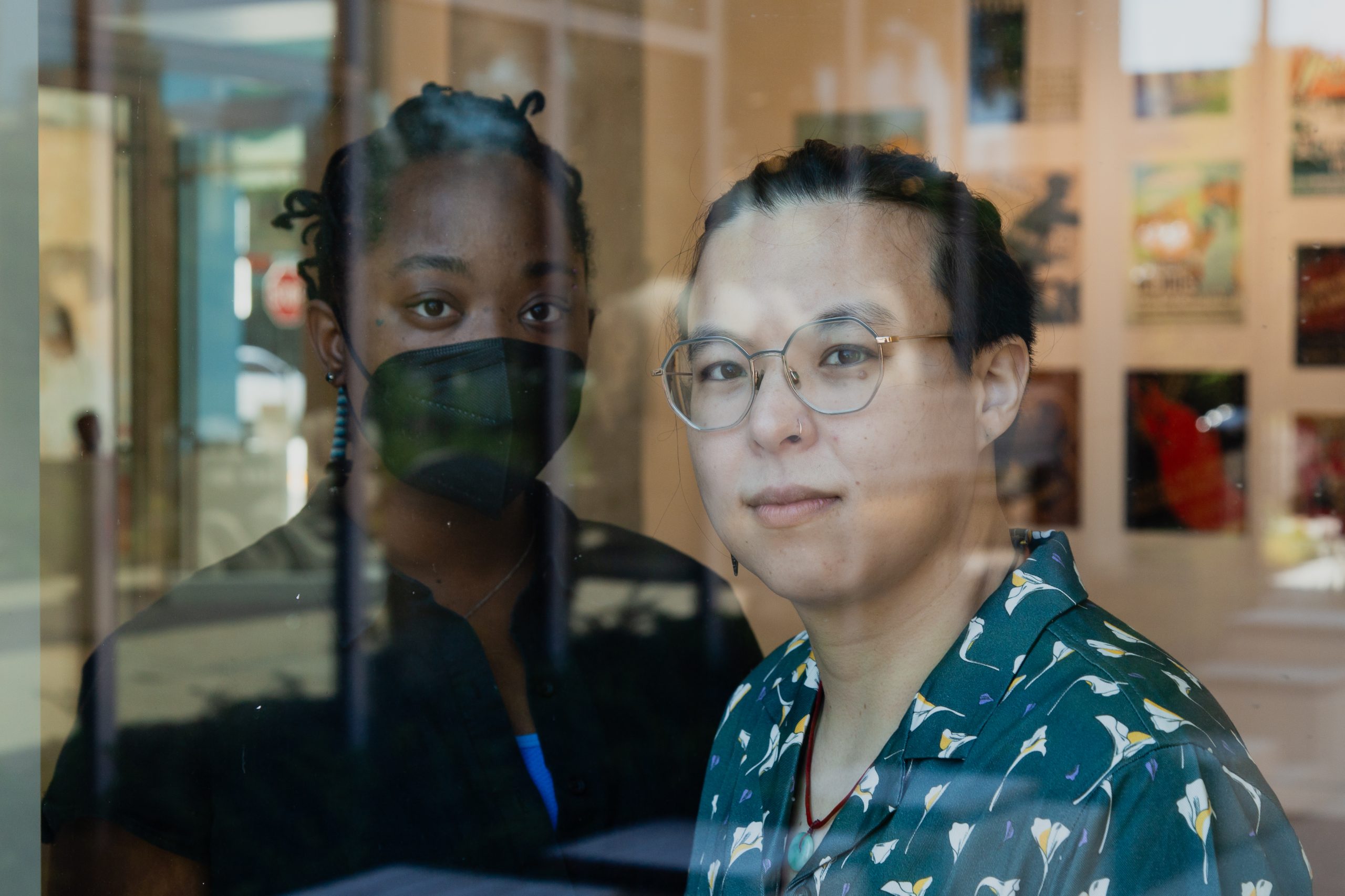 Image: jellystone robinson frazier (pictured left) and Liú méi zhì huì (pictured right) stand perpendicular to each other closely behind a window in an exhibition space of the National Public Housing Museum. Image by Joshua Clay Johnson.