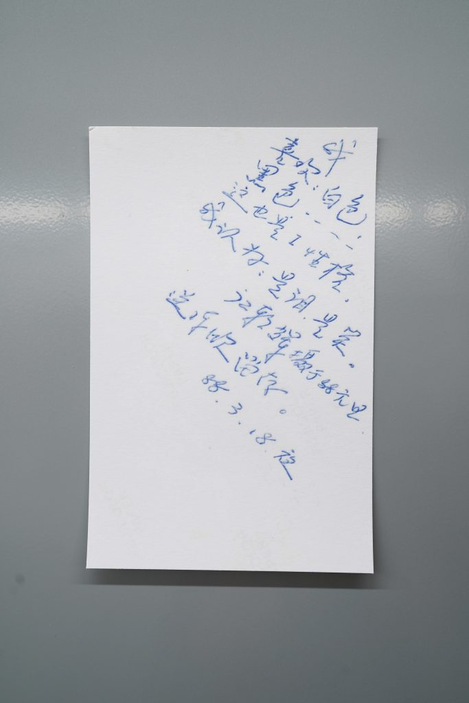 江麟冶作品《父亲肖像背面的手写文字》（1988 / 2025 年再版）展览现场，喷墨打印，并以磁条固定于金属板上。文字内容：
我
喜欢：白色
黑……
这也是 I 个性
我想它是泪，是笑
江朝辉摄于一九八八年元旦
赠陈欣留存
1988 年 3 月 18 日夜。
照片由艺术家提供。