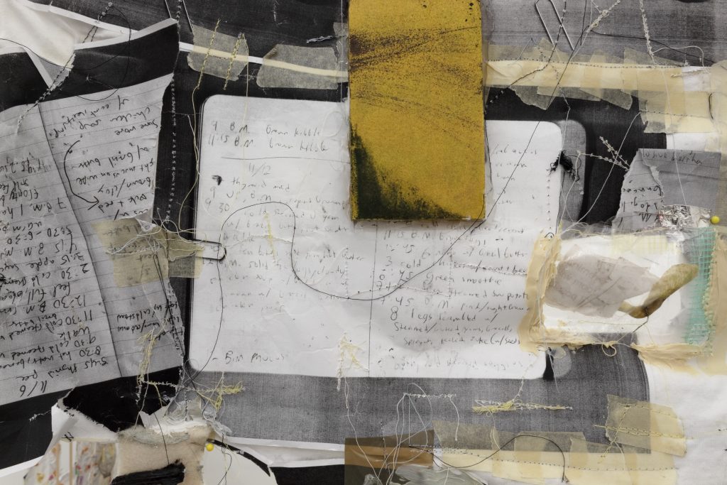 Various journal pages with handwritten notes are stitched with thread and taped onto the surface of a white cotton t-shirt.