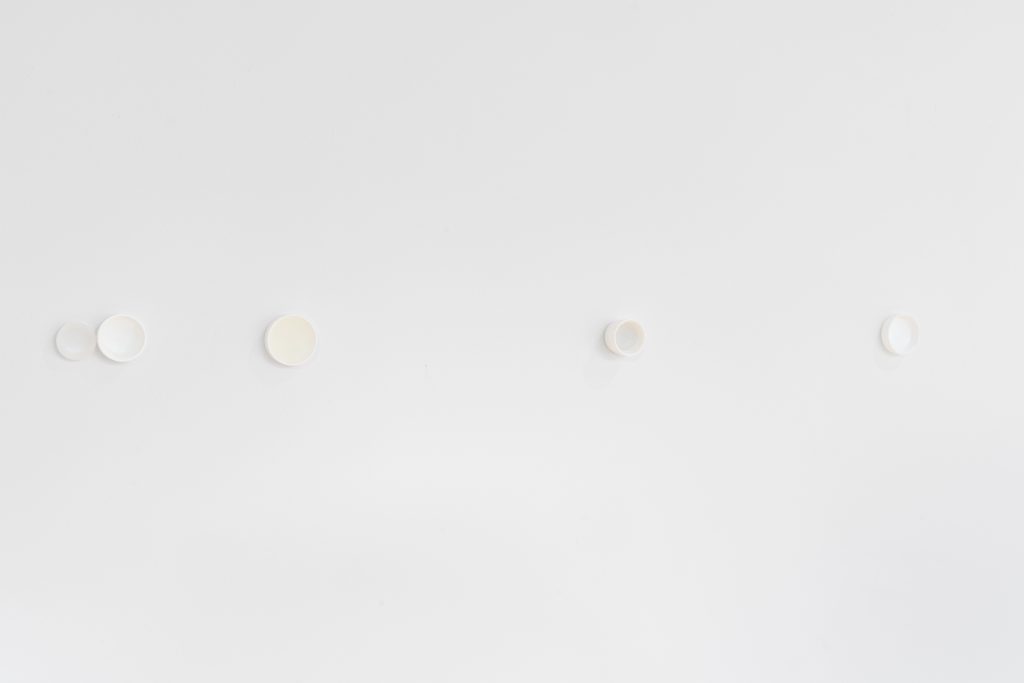 Image: (d)olor atemporal, 2024. Installation view, "A toxin threatens, but it also beckons," Gallery 400. White cube gallery space with plastic crucibles affixed to the wall of the same color. Image courtesy of Prairie, Chicago.