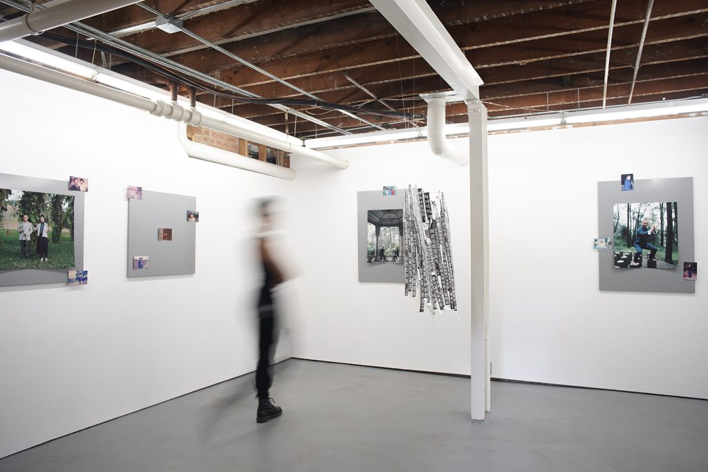 江麟冶个展《Scavenger Hunt》展览现场。中央悬挂的是雕塑作品《摘录自父亲小说〈深圳故事〉》（2025），由父亲的文字片段构成。由左至右依次为：《我与父亲》（2018）、《妈妈和爸爸》（1989 / 2025 年再版）、《父母》（2018）与《父亲》（2018）。以上作品均为喷墨打印，并以磁条固定于金属板上。照片由艺术家提供。
