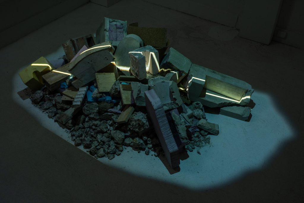 A pile of rubble is illuminated by a band of light.