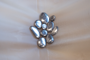 Close up photo of the piece stone babies, which sits upon The material plane. Both pieces are by bex ya yolk. stone babies appears as a collection of metallic stones cradled together. Photo courtesy of Chicago Artists Coalition.