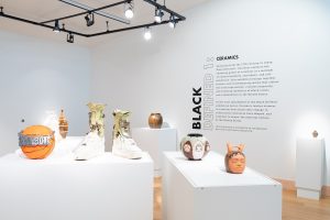 Installation View, “Black Defined 1: Ceramics,” 2025. Milwaukee’s Bronzeville Center of the Arts. Ceramic works on pedestals paired with the intro text on a white wall. Photo: Daniel McCullough.