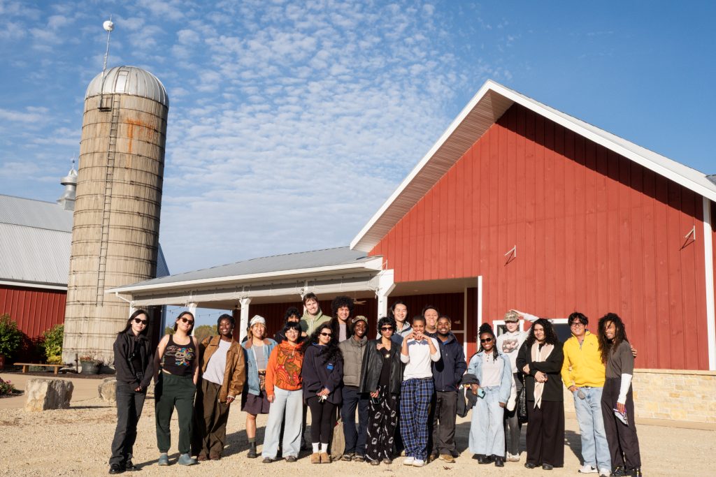 Savannah Sanctuary in Dodgeville, WI. All the participants pictured in front of a red barn and silo. They stand shoulder to shoulder in two relaxed rows, with arms around each other. Photo by and courtesy of Max Li.