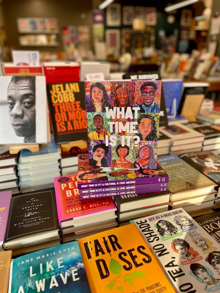 Image: What Time Is It? A Cultural and Civic Archive book sits on a bookshelf at Women and Children First Bookstore, and independent feminist bookstore in Chicago’s Andersonville neighborhood. Surrounding the book are other titles like: Fair Doses: An Insider’s Story About the Global Pandemic, No Tea No Shade: Life As A Drag Queen, and James Baldwin: A Love Story. Photograph by Irina Zadov.