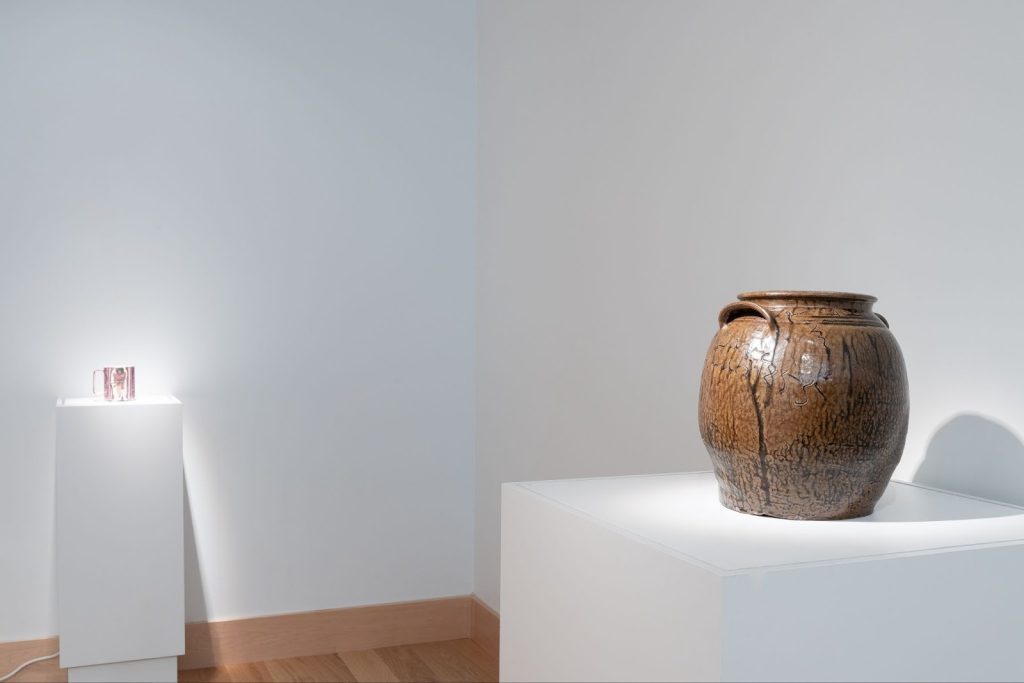 Installation View, “Black Defined 1: Ceramics,” 2025. Milwaukee’s Bronzeville Center of the Arts. A diagonal relationship of two white pedestals: in the foreground are David Drake’s Jar and Michelle Erickson’s Remember. Photo: