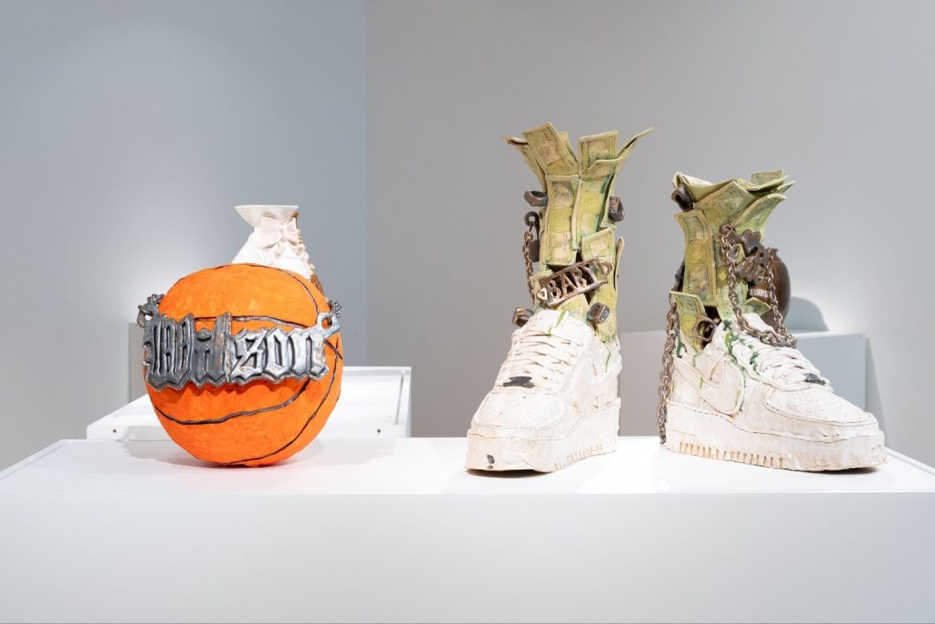 Installation View, “Black Defined 1: Ceramics,” 2025. Milwaukee’s Bronzeville Center of the Arts. Janiece Maddox’s Wilson’s and Ca$h AF1. A ceramic basketball with a Wilson’s nameplate paired with Air Force Ones with fake money and chains emerging. Photo: Daniel McCullough.