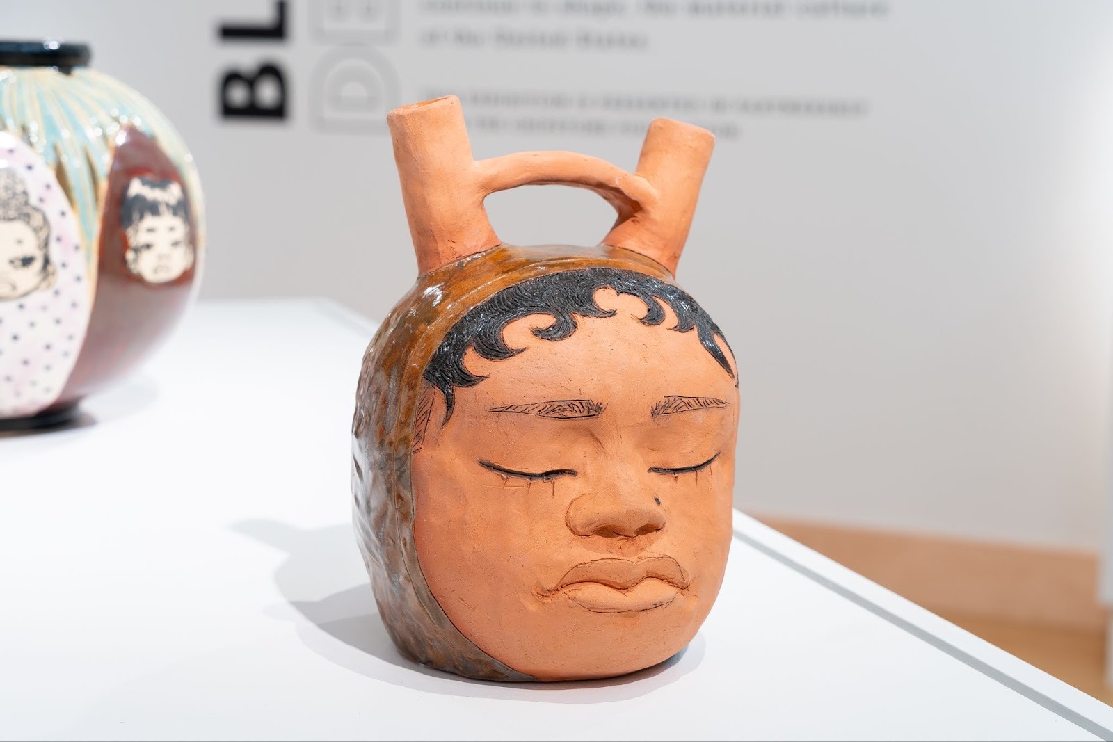 Image: Sydnie Jimenez, Double Spouted Hoodie Vessel, 2023, glazed terracotta. Two-spouted vessel with fingerwaves and eyes closed. Photo: Daniel McCullough