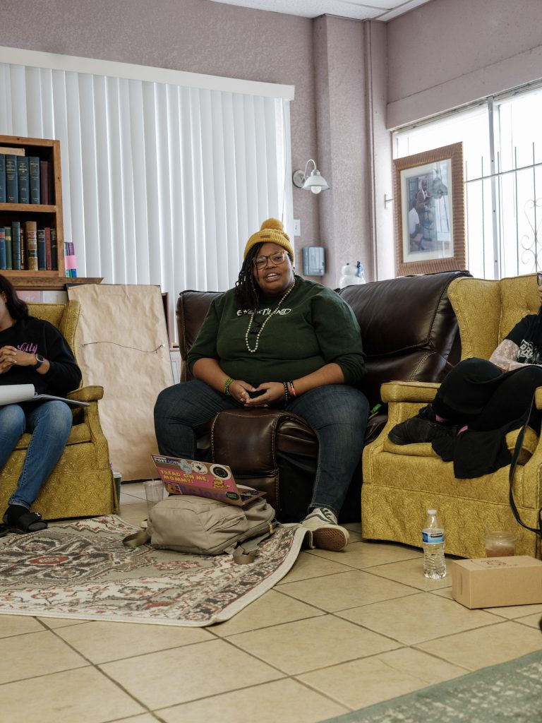 Image: Melissa Ferrer Civil, the director of B-REAL Academy, speak at The KC Defender at their Fall retreat, which took place at Willa’s Books & Vinyl. Two other folks can be partially seen on either side of Melissa Ferrer Civil. Photo made by Vaughan Harrison.