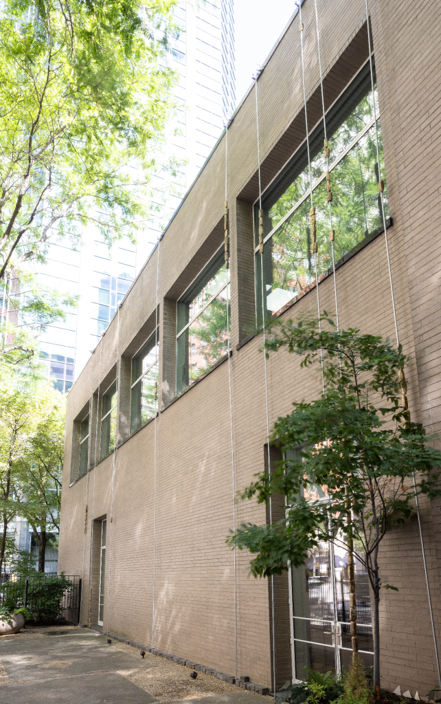Installation view: Temitayo Ogunbiyi, You will count those whose names you may never know (aba-cus), 2019. Long metal poles stretch from the ground in the garden area of The Arts Club to the roofline. Suspended on the poles are small golden stones. Courtesy The Arts Club of Chicago. Photograph by Michael Tropea.