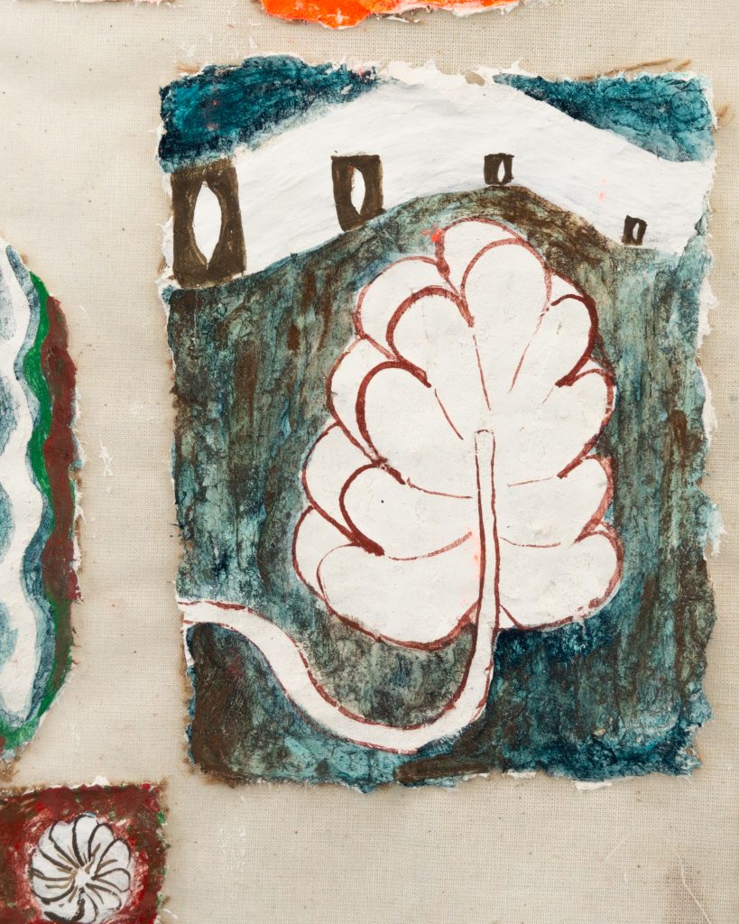 Sending a Picture (garment front), 2026. A fresco tile with a floral design against a muddied blue background is attached to muslin. Edges of other fresco tiles are visible on the left side of the image and near the top.