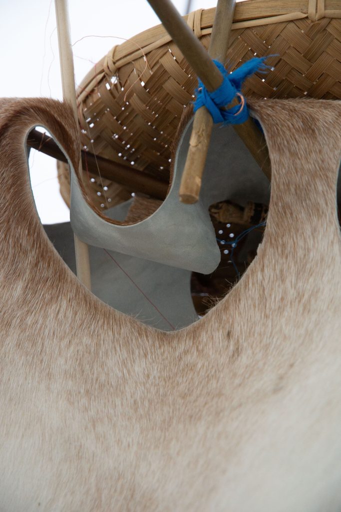 Detail shot of Hai Wen Lin's Bayin ensemble (transmitter). A woven basket is attached to bamboo rods fastened together with copper wire and blue silk. Animal hide drapes from the structure.
