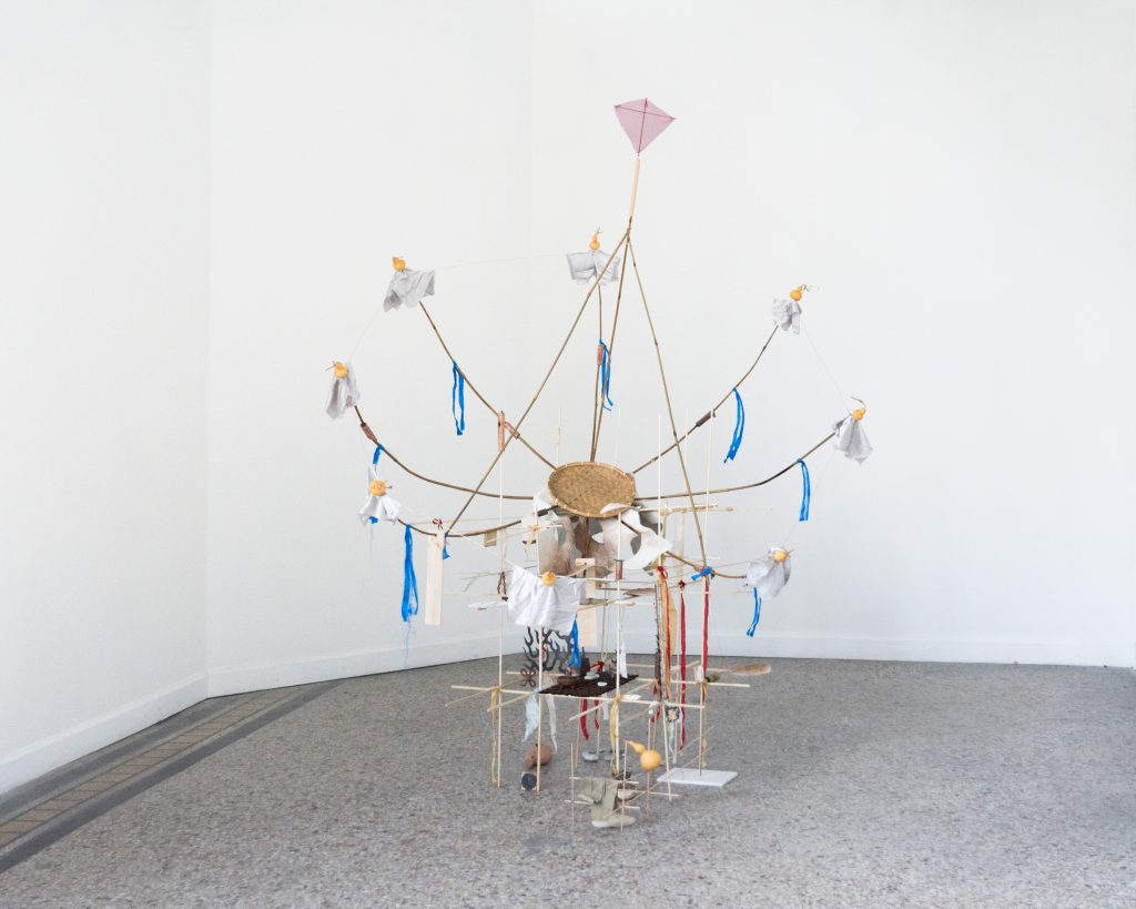 Bayin ensemble (transmitter), 2026. An assemblage sculpture resembling a satellite transmitter is fabricated from various materials, including wooden rods, bamboo, gourds, blue silk, red silk, pale white silk, ceramic instruments, fresco pieces, embroidered hide, metal charms, etc. 