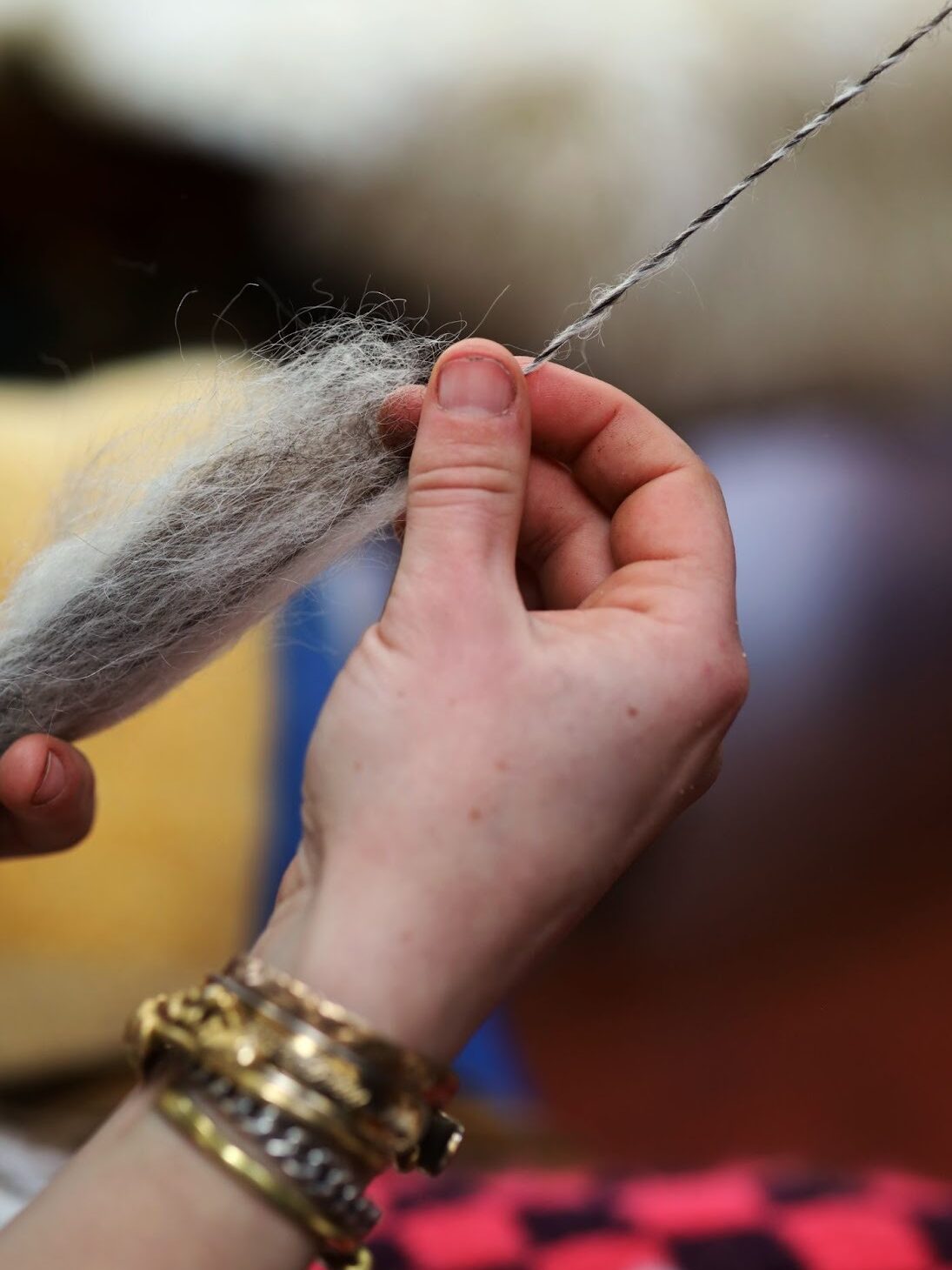 A close-up of Rachel spinning yarn on the wheel in her home with wool from Fiber Fleet: a black Icelandic wool combed together with white Mohair from her goat, Cammie. Image by Viki Stark.