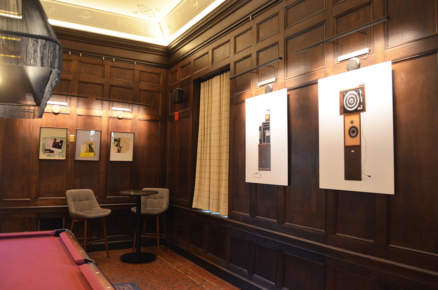 Image: Five works by Jen Everett on display at 21c Museum Hotel St. Louis, in the billiards room. The works hang on dark wood walls and a pool table can be seen to the left. Image courtesy of 21c Museum Hotel St. Louis.
