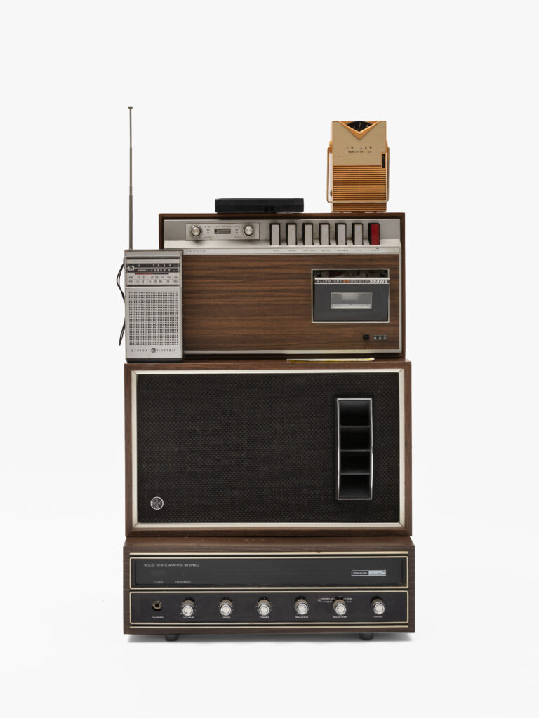 Jen Everett, Untitled, from the series Unheard Sounds, Come Through, 2025. Found objects. Dimensions Variable. Installation: 30 x 16.25 x 15". The image shows a stack of vintage stereos and other vintage audio equipment. Courtesy of the artist and Rivalry Projects, Buffalo, NY.