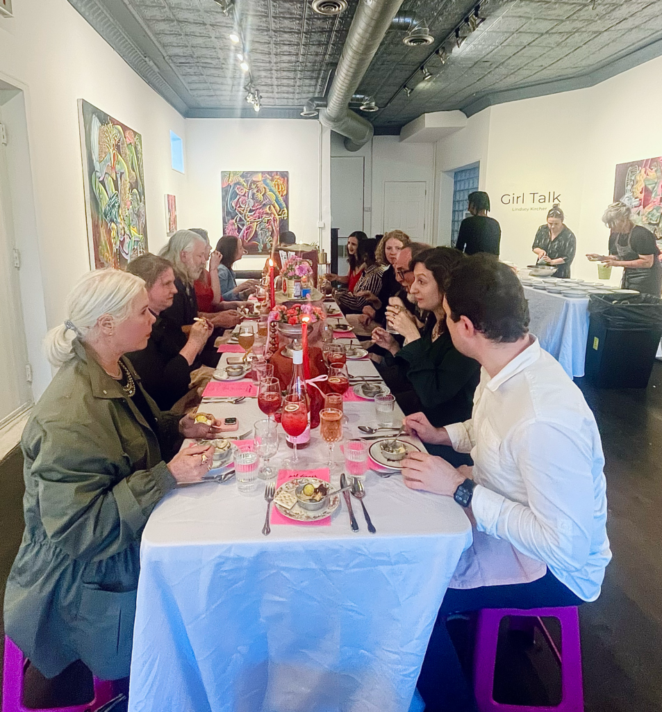 Image (right): A view of a group of people eating around a long, rectangular table at Girl Dinner. Image courtesy of Lindsey Kircher.