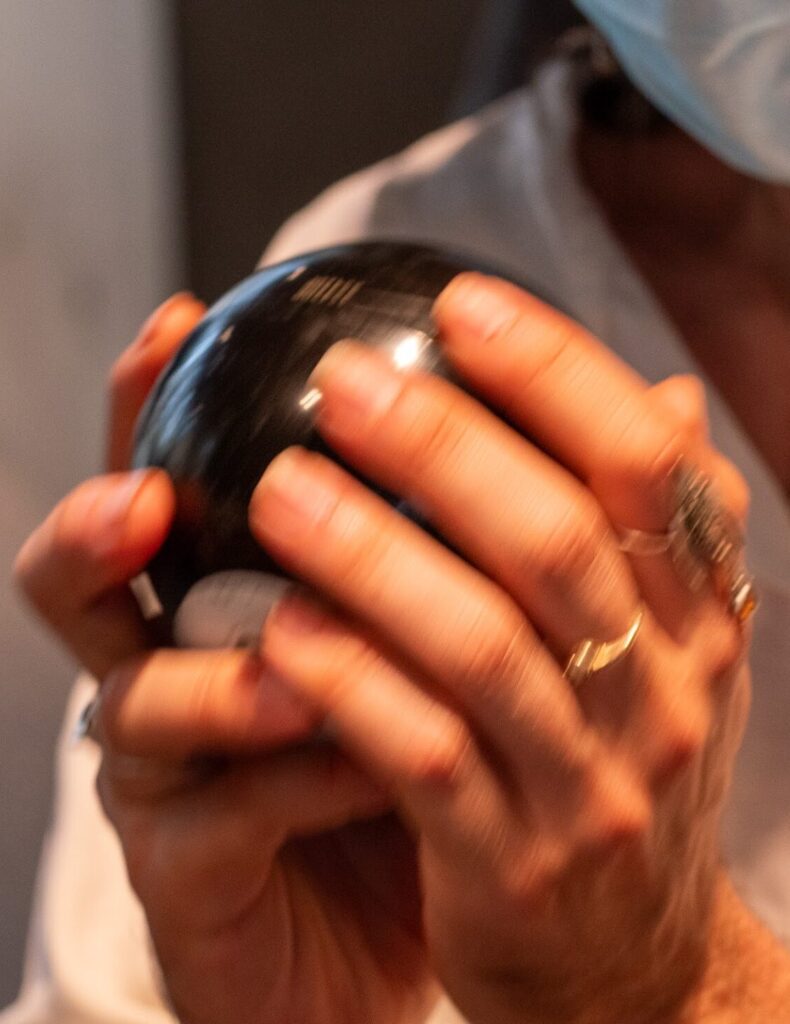 An audience member holds a Magic 8 Ball in between their hands. Photo by Larry Wolf.