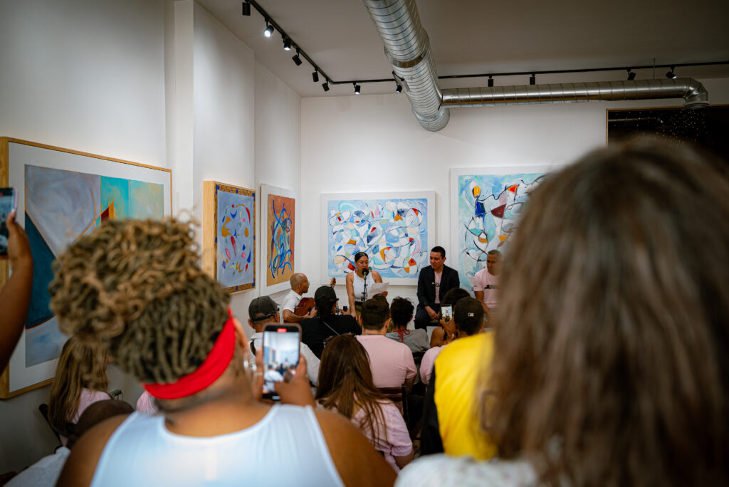 Chicago Poet Laureate Mayda del Valle performs her ekphrastic poem inspired by DIGNIDAD in Le Lo Lai Gallery in front of a large crowd. Photo by Tonal Mondae.