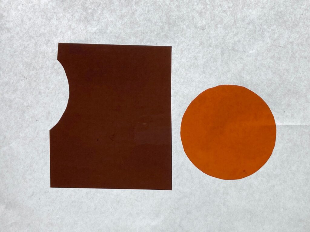 Image: Colors chosen by Andrea Estrada (left) and Ames Meeks (right) that represent their feelings about climate change are featured on a textured grey background. The color of Andrea's on the left is called 511S Bacon Brown and it's shown as a rectangular shape with a small curve intent on the upper left side. The color of Ames' on the right is called 512 - Amber Delight and it's shown as a circular shape. Image courtesy of Adda Farcus. Photograph by Jade Minh-ha Nguyen.