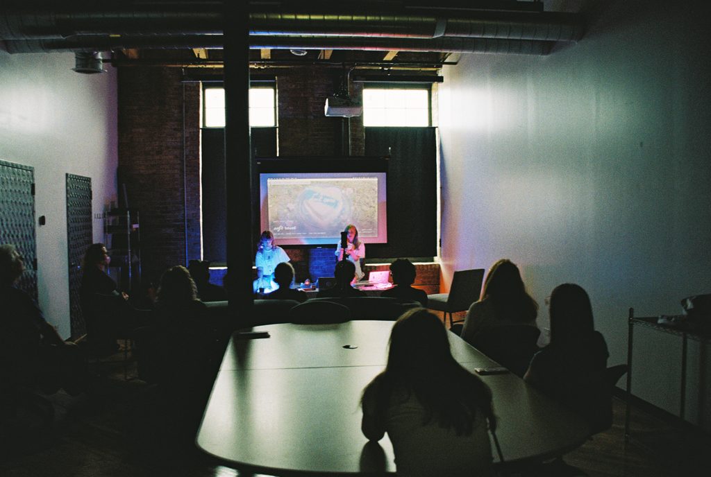 Soft Reset presenting in front of an audience with a projector. Photo courtesy of the artist. 