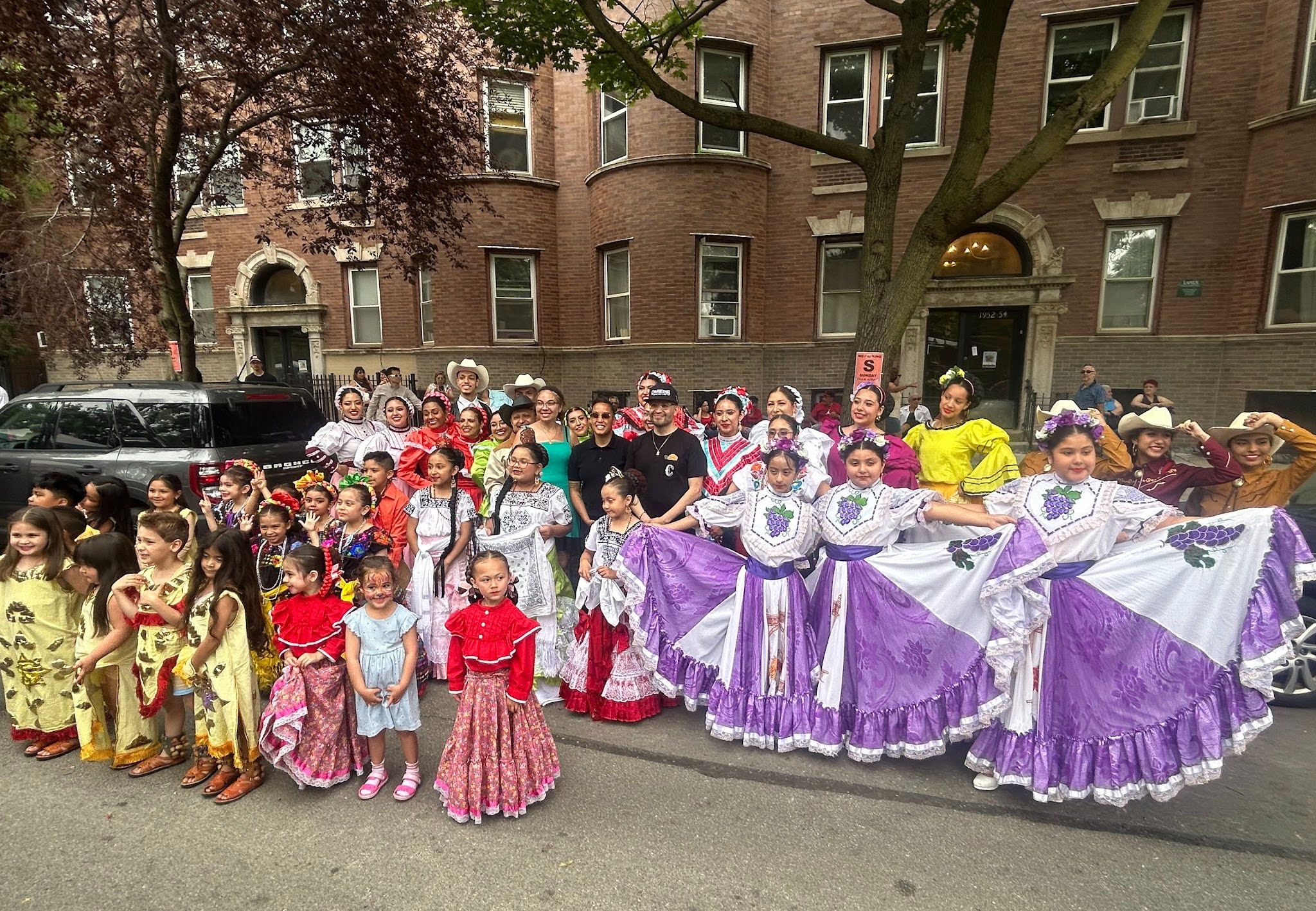 Ballet Folklórico dancers at Calaveras Barber Shop & SMP block party posing with the founder Ofelia Guerra, Alderperson Jesse Fuentes, and Ricardo Sepeda. Photo by Basia Krupa.