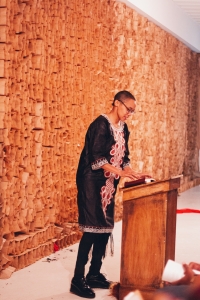 A photo of Tiff Beatty, the unofficial pastor of The People's Church, standing at a podium with her hands on a book, looking down and speaking to the audience. Photo by Candice Majors.